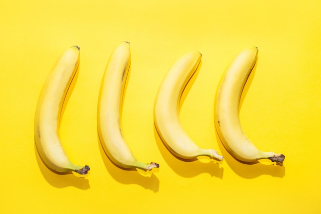 黄色のパステル調の背景にバナナ。最小限のアイデア食品のコンセプト