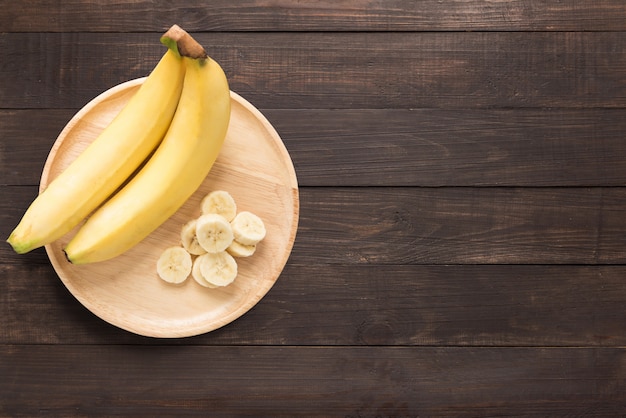 Bananen in een houten schotel op een houten achtergrond. ruimte voor tekst