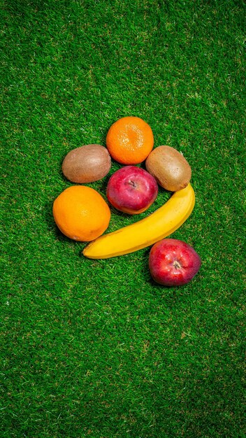 Bananen, rode appels en verschillende vruchten liggen op het gras.