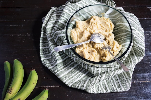 Bananenbiomassa in een kom en nog steeds groen fruit in de linker benedenhoek