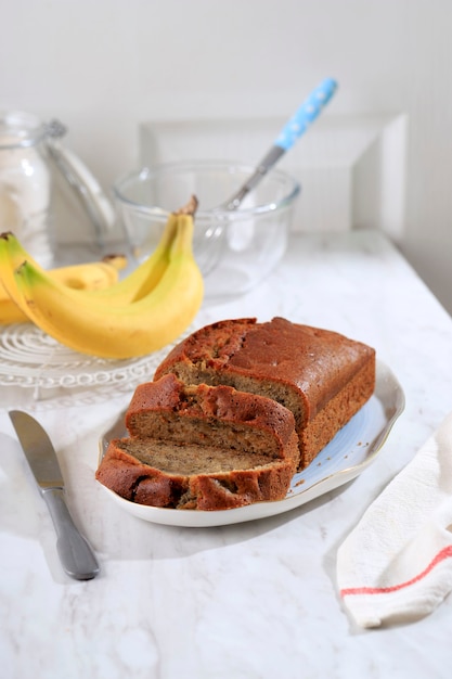 Bananencake gesneden op keramische plaat, heerlijk bananenbroodrecept op wit concept voor bakkerijwinkel, kopieerruimte voor tekst