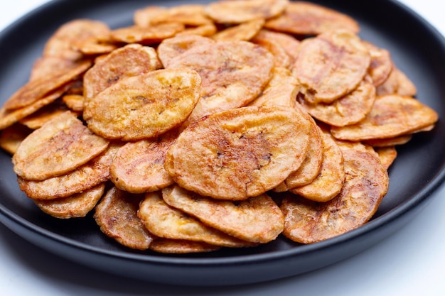 Bananenchips in zwarte plaat op witte achtergrond