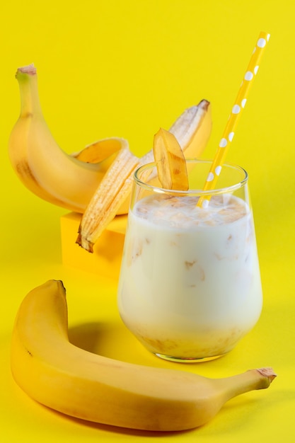 Bananenmelk in een glas en rijpe bananen. Concept van een veganistisch alternatief voor traditionele melk