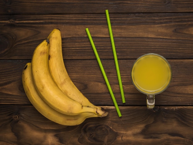 Bananensap en cocktailbuizen op een houten tafel Plat gelegd