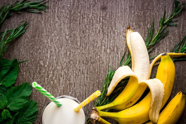 Bananensmoothie en verse banaan op houten tafel