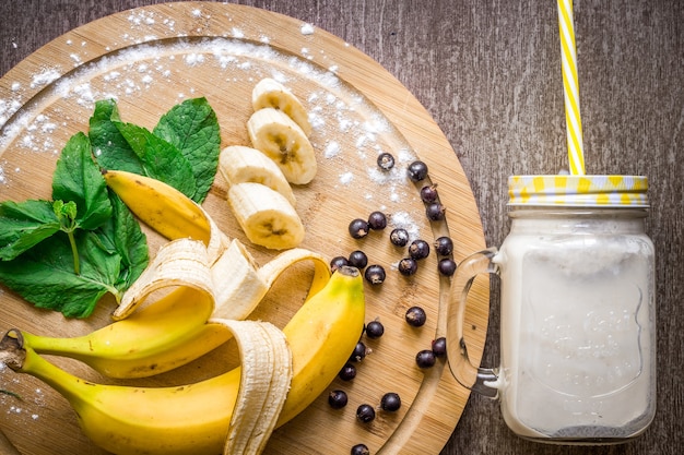 Bananensmoothie en verse banaan op houten tafel