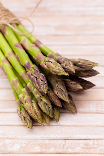 Banches of fresh green asparagus, garlic, on wooden surface, top view