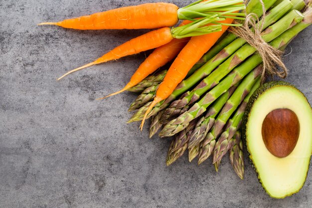 Banches of fresh green asparagus, and vegetables on wood, top view