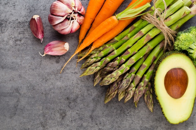 Banches van verse groene asperges en groenten op houten achtergrond, bovenaanzicht