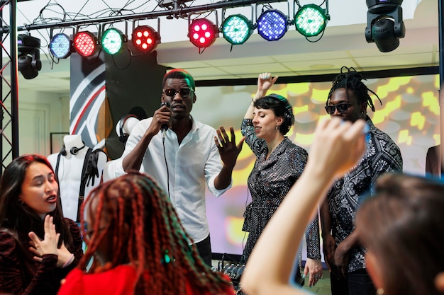 Band optreedt op het podium met schijnwerpers terwijl het publiek juicht en clubt op de dansvloer van de nachtclub. Muzikanten zingen en spelen op een elektronisch muziekfestival live concert in de club