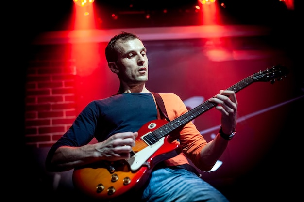 Band performs on stage, rock music concert in a nightclub. Authentic shooting with high iso in challenging lighting conditions. A little bit grain and blurred motion effects.