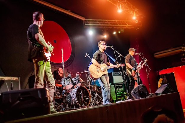 Foto band presteert op het podium, rockmuziekconcert in een nachtclub. authentiek fotograferen met hoge iso in uitdagende lichtomstandigheden. een beetje graan en wazige bewegingseffecten.