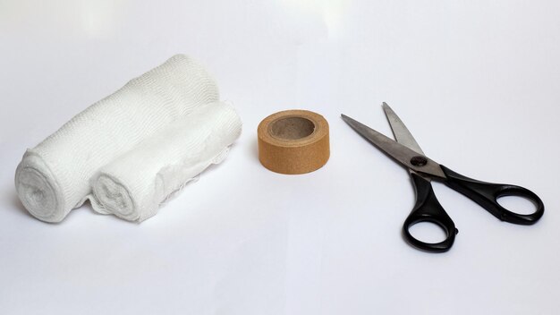 Bandage adhesive plaster and scissors on gray background