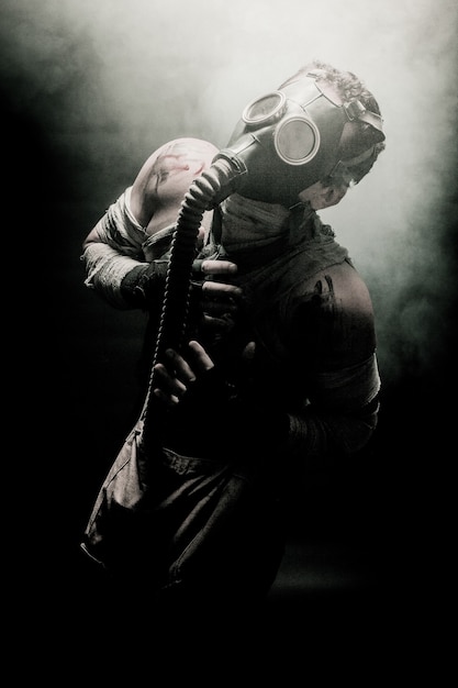 煙に囲まれ、空を見ているガスマスクの包帯男、黙示録後の生存兵。