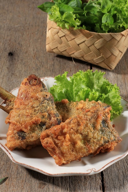 Photo bandeng presto goreng, or fried milkfish cooked with pressure cooker, served with chilli paste (sambal) and fresh vegetable