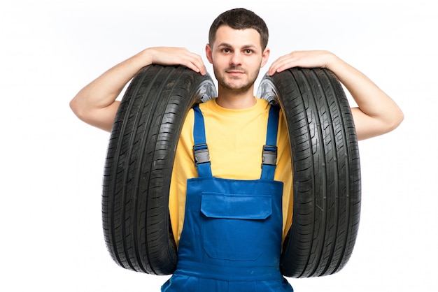 Bandenservice werknemer in blauw uniform houdt autoband