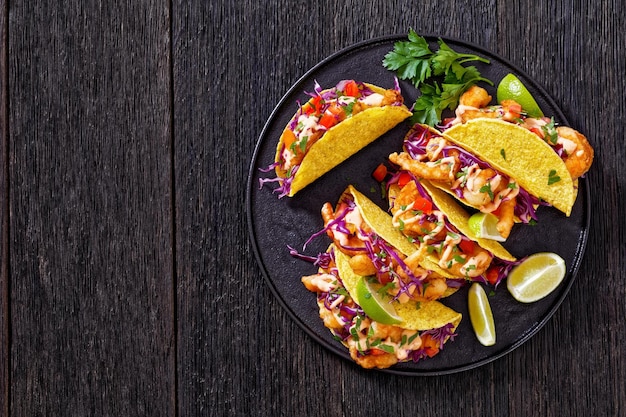 Foto bang bang garnalen taco's op zwarte plaat met saus