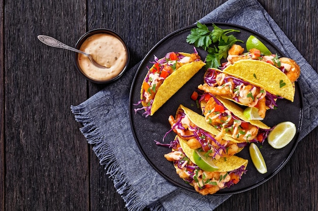 Bang Bang Shrimp Tacos on black plate with sauce