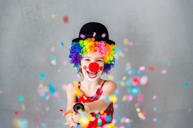 Bang! grappige jongen clown spelen thuis. kind schietpartij popper confetti. 1 april fool's day concept