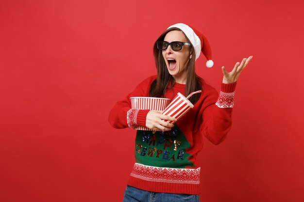 Bang jong Santa meisje in 3d imax bril kijken naar film film, houd popcorn, kopje frisdrank verspreid handen schreeuwen geïsoleerd op rode muur achtergrond. Gelukkig Nieuwjaar 2019 viering vakantie partij concept.