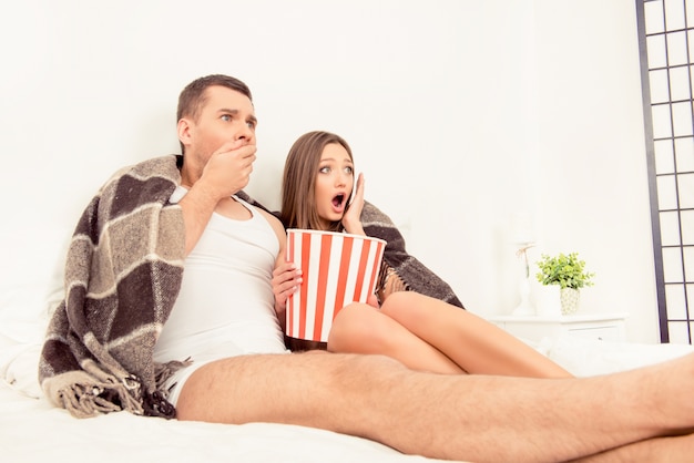 Bang man en vrouw kijken naar horrorfilm met popcorn voor het slapengaan