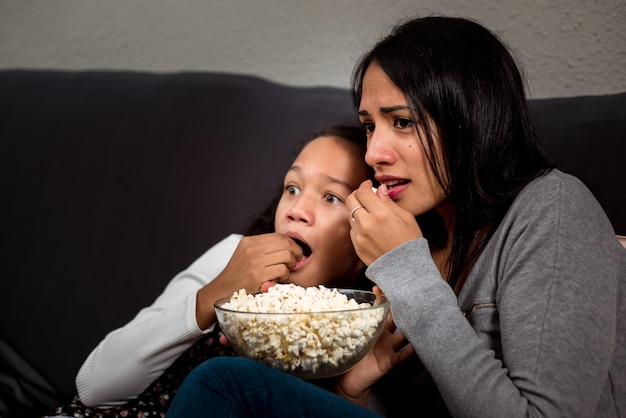 Bang moeder en dochter kijken naar een horrorfilm terwijl ze popcorn eten.