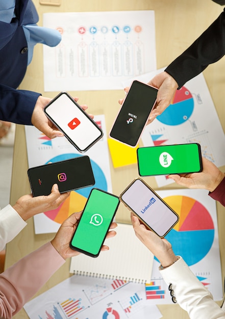 Photo bangkok/thailand - august 06, 2021: people hold smartphones in different brands and operating systems with various logos of social applications, twitter, instagram, tiktok, linkedin, line, youtube.