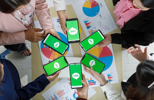 Bangkok/Thailand - August 06, 2021: People hold smartphones in different brands and various operating systems with logos of Line app, one of most popular messege applications.