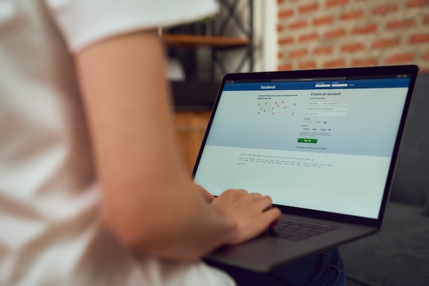 Bangkok, Thailand - February 24, 2020 : Woman hand is pressing the Facebook screen on apple Macbook Pro, Social media are using for information sharing and networking.