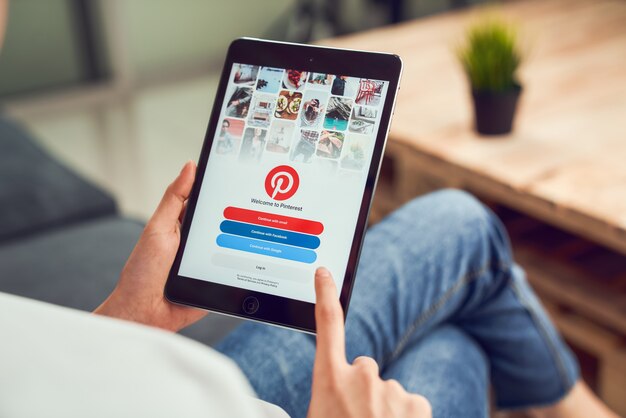 Bangkok, Thailand - January 15, 2020 : woman hand holding tablet and display social Internet service Pinterest on the screen. is an online pinboard that allows people to pin their interesting things.