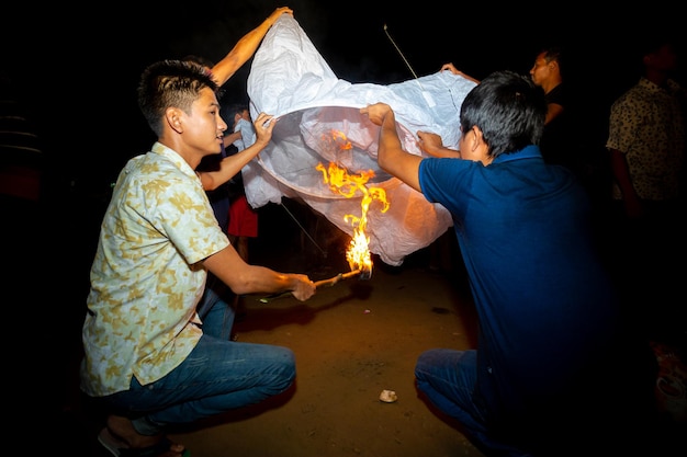 Бангладеш, 12 октября 2019 г. Люди пытаются зажечь бумажные фонарики на фестивале полнолуния Проберона в Кеангмор Бандарбан