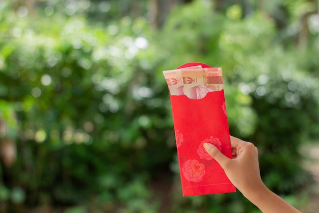 Banjarnegara januari 2023 Red Angpao in één hand gehouden met natuurlijke groene onscherpe achtergrond Chinees Nieuwjaar