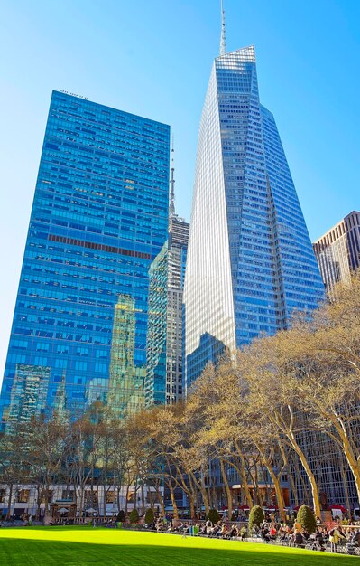 Bank of America skyscraper and Green Lawn of Bryant Park in Midtown Manhattan, New York, USA. Tourists relaxing in the park