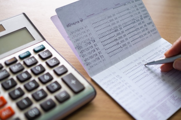 Bank book with pen and calculator on wooden table. Business and financial for plan money saving, stock market concept.