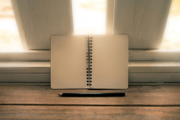 Bank notebook and pencil on wood table vintage tone