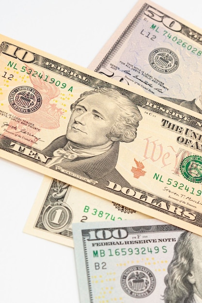 Банкноты в один, десять, пятьдесят и сто долларов США сверху, выделенные на белом фоне