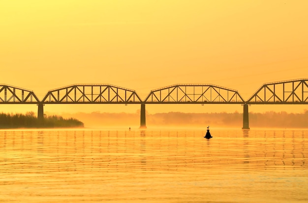 The bank of the Ob River Railway bridge in the morning fog in the morning golden light Novosibirsk