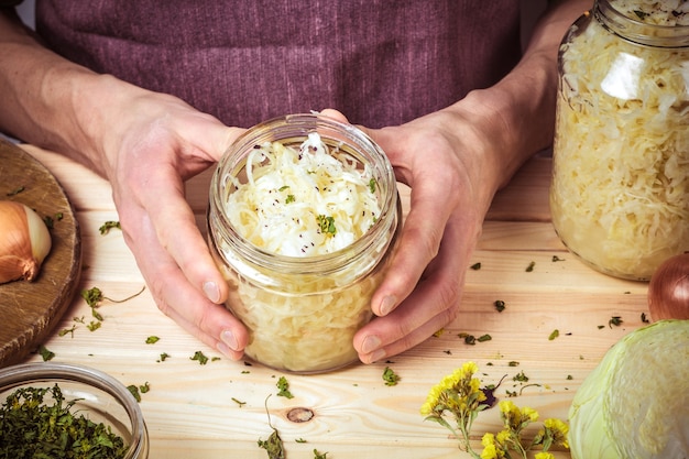 A bank of sauerkraut in the hands of a chef on the background of a table with ingredient