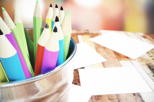 Bank with colored pencils on the wooden table