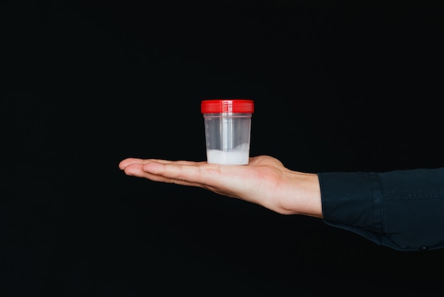 Bank with sperm in a man's hand on a black background