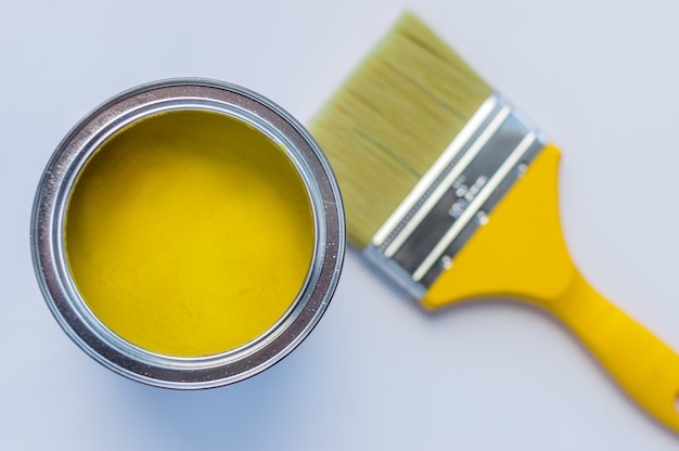 Bank with yellow paint and brush close-up on a white background