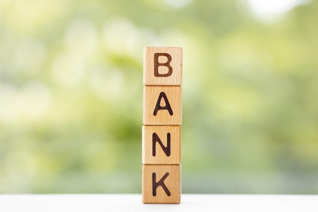 Bank word is written on wooden cubes on a green summer background Closeup of wooden elements