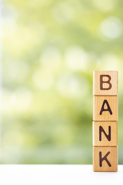 Bank word is written on wooden cubes on a green summer background Closeup of wooden elements