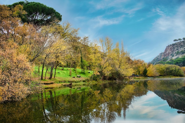 Banken van de rivier de Alberche, Spanje, met weerspiegeling van bomen en bewolkte hemel in wateren.