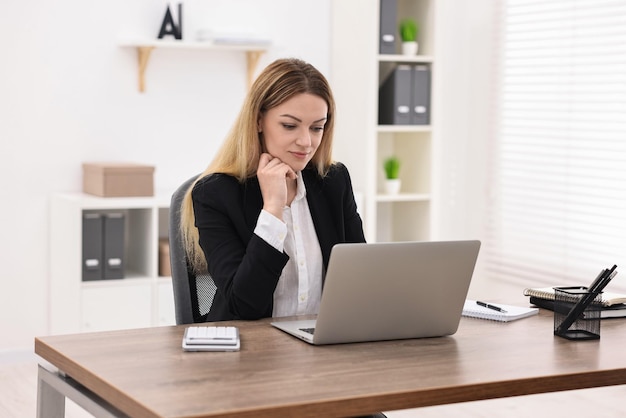 banker using laptop at wooden table in office