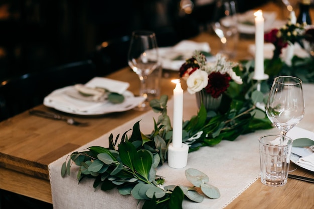 Banket tafelschikking Borden vorken kaarsen op houten tafel met mooie decoratie Bestek en wijnglazen Restaurant gezellig interieur Tafel geserveerd voor speciale gelegenheid Viering concept