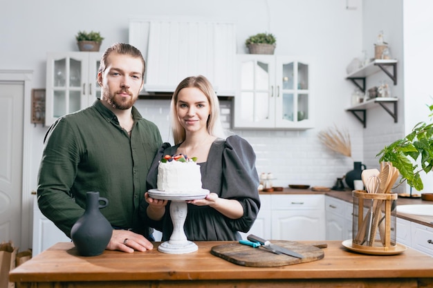 Banketbakker, banketbakker, jonge blanke vrouw met echtgenoot, vriend, man, probeer de smaak van cake op de keukentafel Taarten, cupcakes en zoet dessert