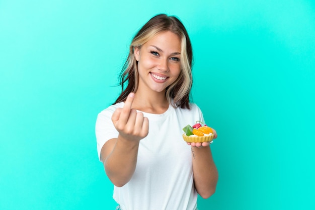 Banketbakker die muffins houdt die op roze achtergrond worden geïsoleerd en een duim omhoog gebaar geeft