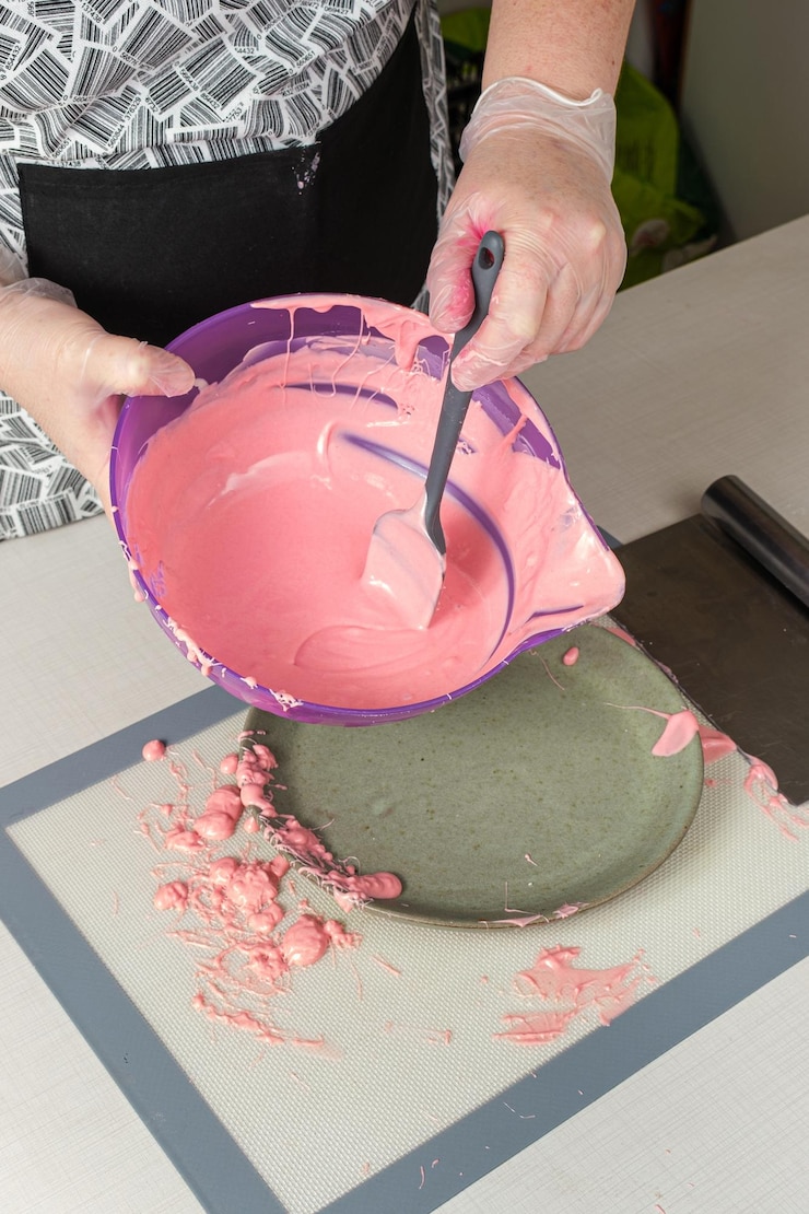 Foto banketbakker mengen met een aardbei ganache spatel.