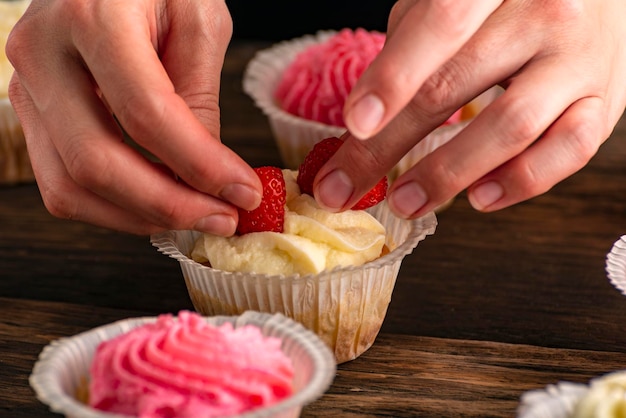 Banketbakker versiert de muffins met verse aardbeien Cupcakes met bessen Close up